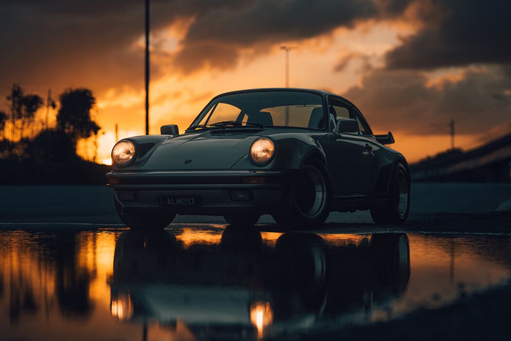 Classic car reflected in water at sunset, edited with North Borders presets