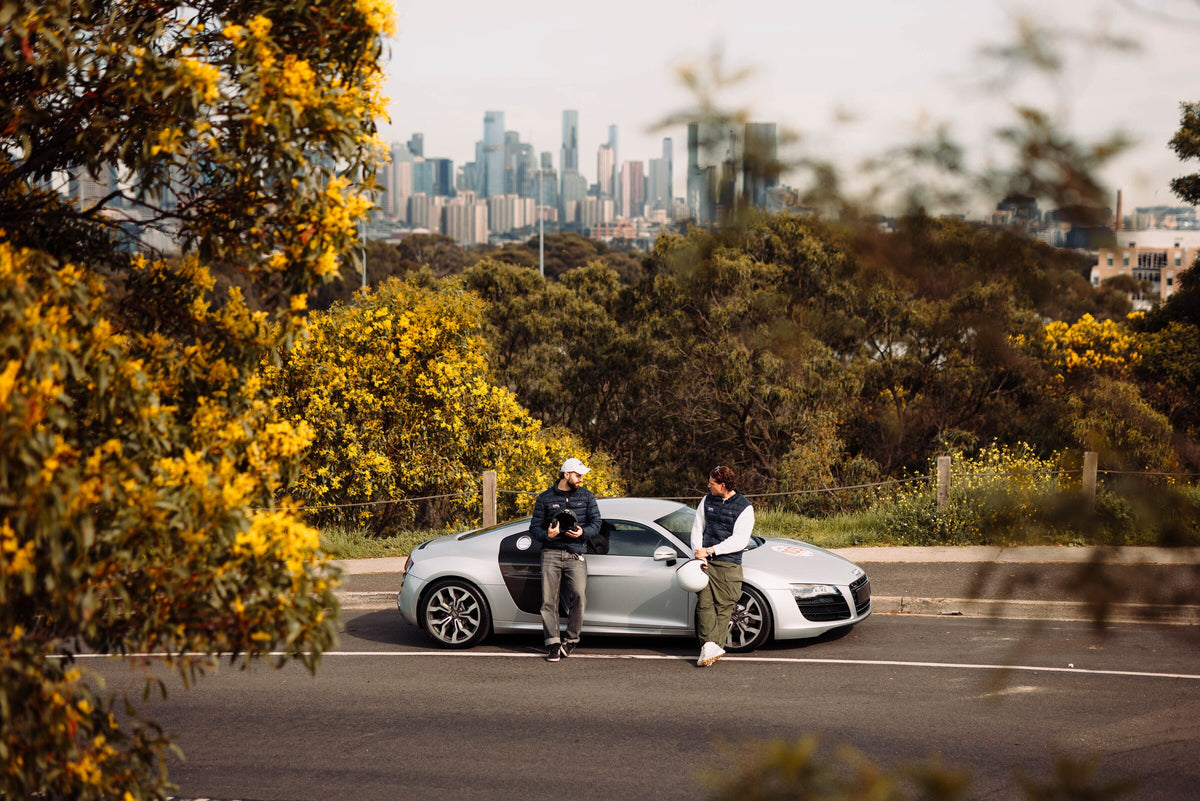 Two people beside a car on a hill above the Melbourne skyline