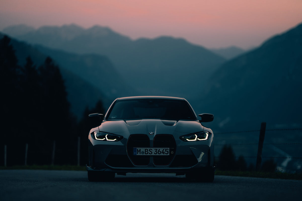 A BMW M4 head on, stopped on a mountain road at dusk